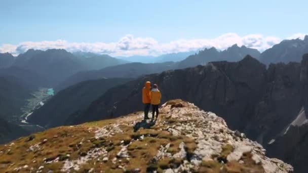 若い観光客のカップル岩の山の上に立っている 男と女は青い空の下でLavaredoの3つのピークの雄大な山脈を見て — ストック動画