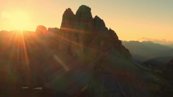 日の出の山の風景です 上昇する太陽の光は バックライトで澄んだ空の航空ビューの下でラバレドの3つのピークの石のない斜面を照らす — ストック動画