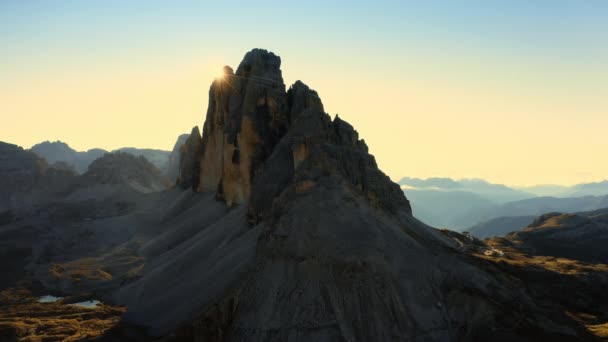 太陽は山脈の上に昇る 砂で覆われた丘陵と緑の谷を持つロッキー山脈 バックライトで日の出の空中ビューでLavaredoの3つのピーク — ストック動画