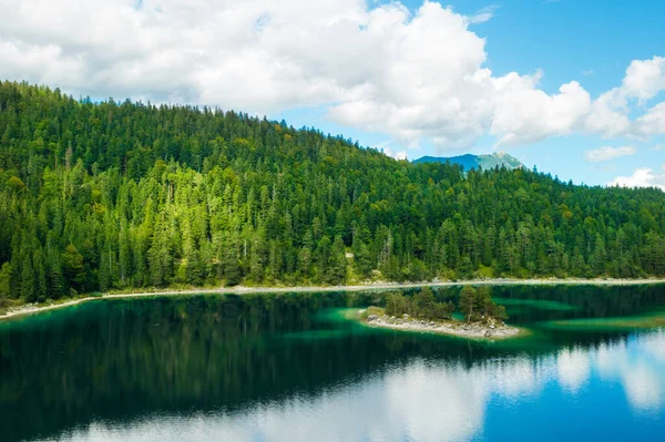 stock image Mountains with spruce trees and clouds are reflected in a forest river. Summer landscape of a riverside. 