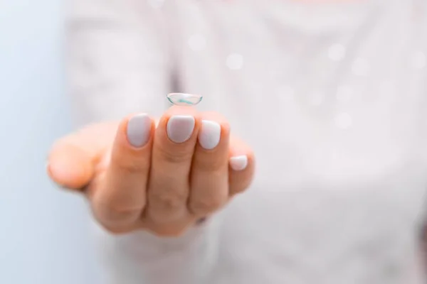 Close up woman holding eye lens on the tip of the finger
