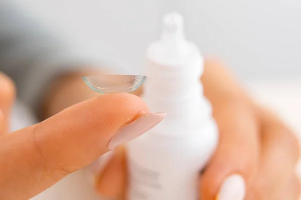 Close up contact lens on the hand and eye drops