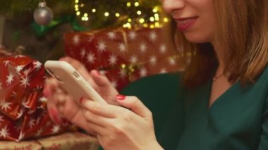 Gülümseyen kadın Noel 'i kutluyor Noel ağacının altında hediyelerle oturuyor.. 