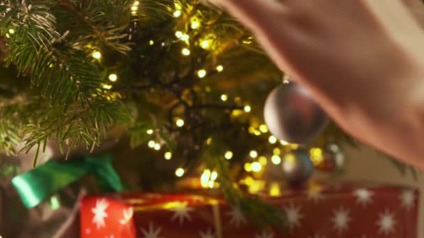 Γυναικεία Χέρια Στολίζουν Χριστουγεννιάτικο Δέντρο Κρέμονται Μπάλα Δώρα Βρίσκονται Κάτω — Αρχείο Βίντεο