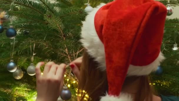 Дівчина Капелюсі Санта Клауса Висить Синю Кульку Ялинці Прикрашати Ялинку — стокове відео