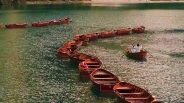 Beyinler, İtalya - 11 Eylül 2022: genç çift Braies Gölü 'nde Braies Gölü' nün yakınındaki gemilerde seyir halindeki ahşap kayıkta oturuyor. Turistler gün batımında İtalya 'da yaz tatilinin tadını çıkarıyorlar.