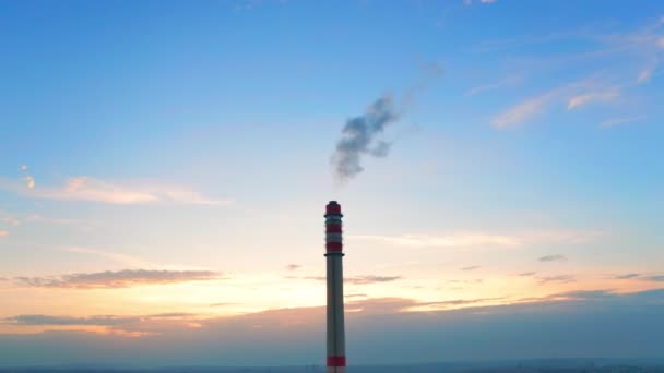 有害な煙の暗いパフは 新鮮な空気を汚染する工業用化学煙突から流出します 巨大なパイプは 水平線の空中ビューでカラフルな夕日に対して立つ — ストック動画