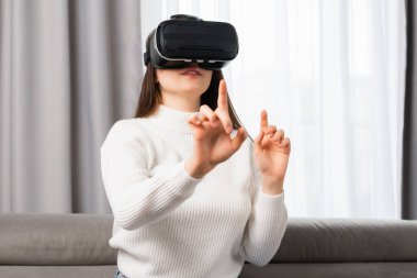 Güzel bir genç kız sanal gerçeklikle etkileşime geçiyor ve oturma odasındaki kasada duran görünmez bir arayüze dokunuyor.