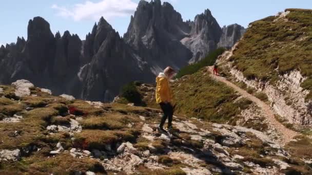 Woman Yellow Jacket Goes Downhill Hiking Path Rocky Mountain Peak — Stockvideo