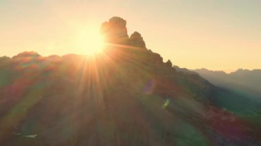 Edges of high peaks at sunrise. Illuminated by the rays of the sun, the rocky peaks of Tre Chime di Lavaredo under a bright sky, an aerial view in backlight