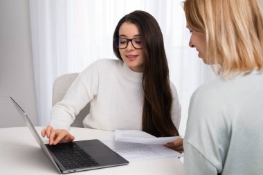 Two young businesswoman discuss new startup project and making presentation using laptop