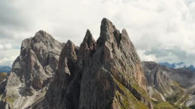 Rocky bare peaks of Seceda mountain against cloudy sky. Giant ridgeline in touristic Italian Alps aerial view from observation point on slope