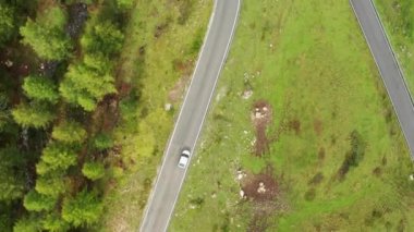 Giau Geçidi 'ndeki Yılan Yolu' nu gezmek için araba sürüyorum. Tepe yamacında beyaz araç asfalt yol kıvrımında döner.