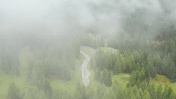 霧の雲は アルパイン山の秋の牧草地の間でスネークロード巻きカバー 霧深い朝に森に囲まれたスネークロードをオートバイでドライブ — ストック動画