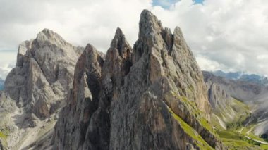 Observation point against giant Seceda mountain with rocky peaks under cloudy sky. Popular tourist attraction in Italian Alps aerial view