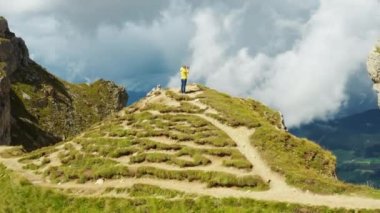 Kadın, Seceda Dağı 'nın tepede otlarla kaplanmış şekilde dururken fotoğraflarını çekiyor. Kadın turist, İtalyan Alpleri 'nin hava manzarasını inceliyor.