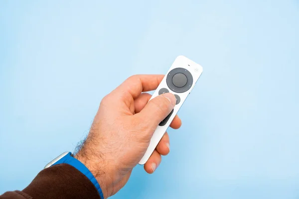 Apple TV 4k Remote controller in mans hand on the blue background, February 2022, Prague, Czech Republic