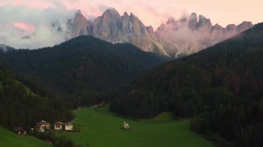 Santa Maddalena köyünün muhteşem manzarası St. Johann eski kilisesi ve Dolomites Geisler dağ grubu vadide Val di Funes pembe gün batımında. 