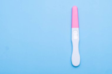 Unused pink and white pregnancy test on the blue background with copy space