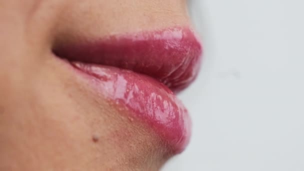 嘴唇上有明亮粉红光泽的女人咧嘴笑着 露出洁白的牙齿 在白色背景下女性脸的下半部分特写 — 图库视频影像