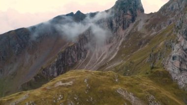 Çıplak kayalıklarla çevrili dağlık yamaçlarda otlamak için çayırlar var. Hafif bulutlar otlakları kahverengi otlarla kaplar koyun sürüleri için.