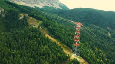 Dağlardaki ağaçlar arasında iletim hattı kulesi.