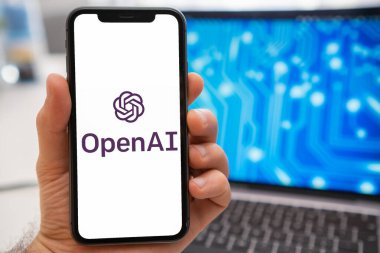 Cep telefonu ekranında yapay zeka logosu ve arka plandaki dizüstü bilgisayar ekranında, Mart 2023, Prag, Çek Cumhuriyeti 