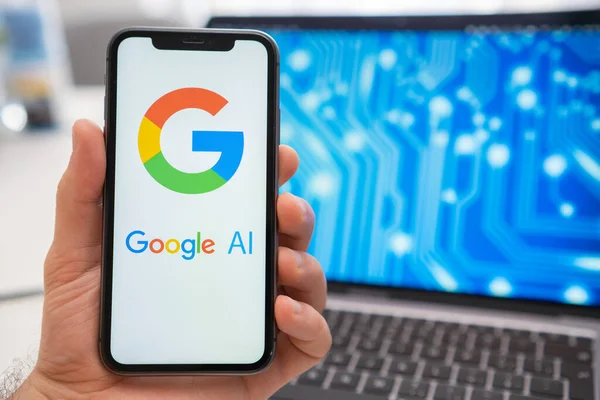 Google Yapay Zeka logosu cep telefonu ekranında ve sinir ağında arka plandaki dizüstü bilgisayar ekranında, Mart 2023, Prag, Çek Cumhuriyeti 