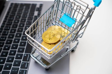 Bilgisayarında Bitcoin olan oyuncak bir alışveriş arabasının en üst görüntüsü. Ticaret konsepti. 