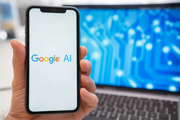 Bir adam ekranında Google yapay zeka sinir ağı logosu olan bir akıllı telefonu ve arka planda sıçrama ekranında nöron gösteren bir dizüstü bilgisayarı tutuyor. Mart 2023, Prag, Çek Cumhuriyeti 