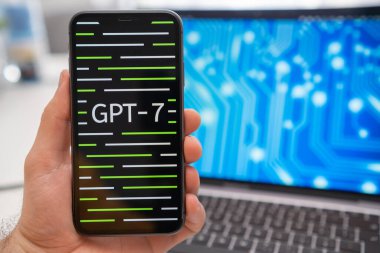 Elinde GPT 7 sinir ağı logosu olan bir akıllı telefon ve arka planda sıçrama ekranında nöron gösteren bir dizüstü bilgisayar tutan bir adam. Mart 2023, Prag, Çek Cumhuriyeti 