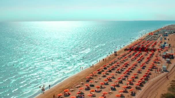 観光客は青い水と光の波でアドリア海のリゾートで夏の休暇をお楽しみください 傘とサンラウンジのビーチの空中ビュー — ストック動画