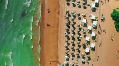 Venedik yakınlarındaki güçlü turkuaz Adriyatik deniz yıkama dalgaları. Turistler yaz tatili havacılık manzarasında güneşli şemsiyeler altında dinlenirler.