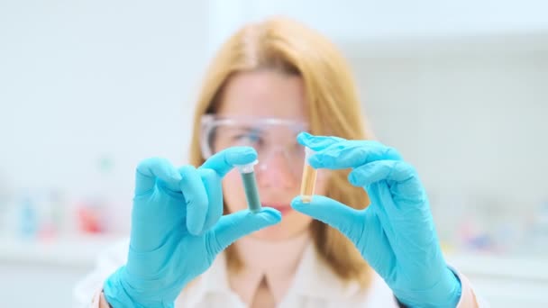 Wissenschaftler Gummihandschuhen Schütteln Reagenzgläser Mit Blauen Und Gelben Flüssigkeitsproben Blonde — Stockvideo