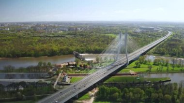 Güneşli Wroclaw 'a karşı Oder nehri boyunca uzanan uzun pilon köprüsü. Manzaralı şehir parkları arasındaki Redzinski Köprüsü 'nde arabalar sürüyor