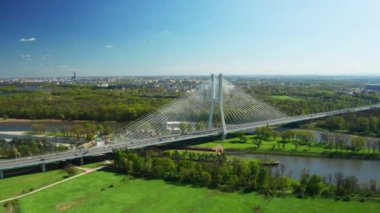 Arabalar, açık mavi gökyüzünün altında, kablo destekli köprüden geçiyor. Güneşli baharda Oder nehrinin üzerindeki büyük Redzinski Köprüsü Wroclaw hava manzarasına açılıyor.