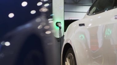 PRAG, CZECH REPUBLIC - 12 Kasım 2022: çevre dostu istasyonda temiz alternatif enerjiyle yüklü beyaz elektrikli araba. Tıpası olan şarj bloğuna bağlı araç