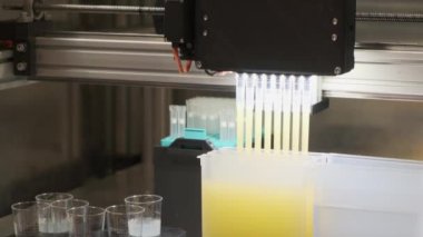 PRAG, CZECH REPUBLIC - 12 Kasım 2022: Laboratuvarda bilimsel analiz için malzeme örnekleme. Profesyonel ekipmanlar sarı sıvıyı bardaklara döküyor.