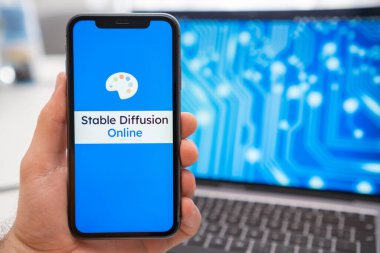 Cep telefonu ekranında sabit difüzyon modeli yapay zeka logosu ve arka plandaki dizüstü bilgisayar ekranında, Mart 2023, Prag, Çek Cumhuriyeti.