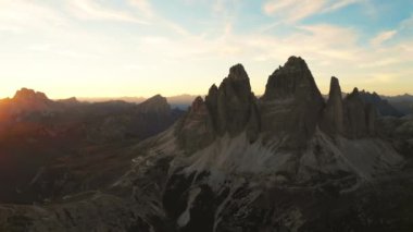 Günbatımları ılık parıltı kayalık dağ sırasını kucaklıyor. Tre Cime di Lavaredo etekleri arka planda çarpıcı bir siluet oluşturur..