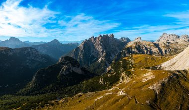 Tre Cime di Lavaredos Dağ Massif, Yüksek Taş Sütunlar, ve Gün Batımından Aydınlanan Savaşa Benzeyen Tepeler, Beyaz Bulutlar Arasındaki Mavi Gökyüzü