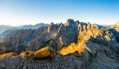 Edges of high peaks at sunrise. Illuminated by the rays of the sun, the craggy peaks of Tre Chime di Lavaredo under a clear sky aerial view in backlight