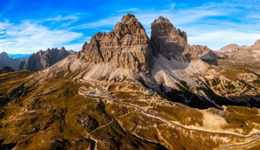Lavaredo 'nun Üç Tepesi' nin Havadan Görünümü, Alp Dağları Beyaz Bulutlu Mavi Gökyüzü 'nün Altında, Rocky Tepeleri Geniş Gölgeli Kanyon' un Üzerinde, Güneşin Sıcaklığında Banyo Yapıyor..