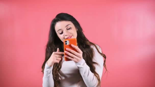 喜んで楽しい表情の女性は スマートフォンでソーシャルメディアをスクロールします 長い緩い髪の女性は インターネット上のニュースフィードを探索楽しんでいます — ストック動画