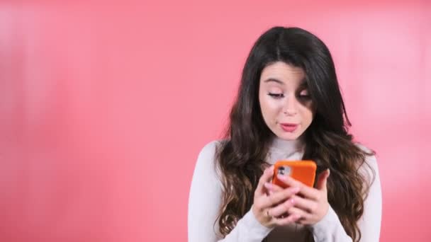 Giovane Donna Con Espressione Deliziata Guarda Smartphone Indicando Dito Muro — Video Stock