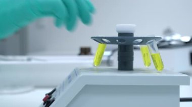 Bilim adamları mikro-fosin cihazına DNA analizi için numuneleri işlemek üzere santrifüj tekniklerini kullanan bir test tüpü yerleştiriyor..