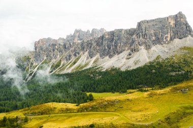  Rocky Dolomite Alpleri dağın eteğindeki bulutlar ve yeşil ormanlarla kaplı.. 
