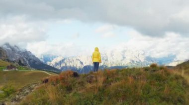 Yürüyüşçü Giau Geçidi 'nin etrafındaki yüksek dağ uçurumlarını keşfediyor. Dişi turist tepenin üstünde duruyor. Mavi gökyüzüne karşı engin dağ vadisini inceliyor.