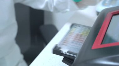 Laboratuvar çalışanı mikroplaka okuyucusundan mikroplakaları alıyor. Tıbbi araştırma laboratuvarında biyokimyasal analiz.
