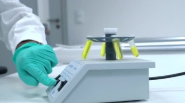Bir bilim adamı DNA analizi için hazırlanan numuneleri sallamak ya da santrifüj etmek amacıyla mikro santrifüje bir test tüpü yerleştirir..